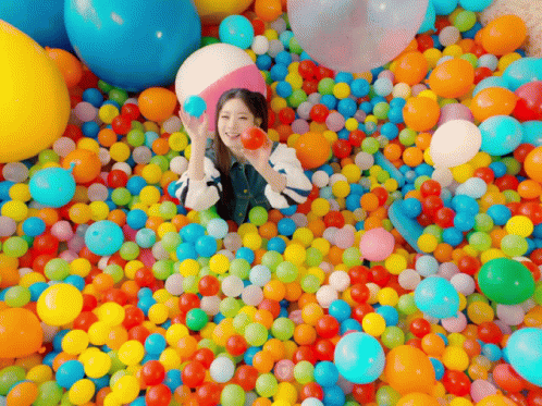Woman Laying In Ball Pit Holding Ball GIF