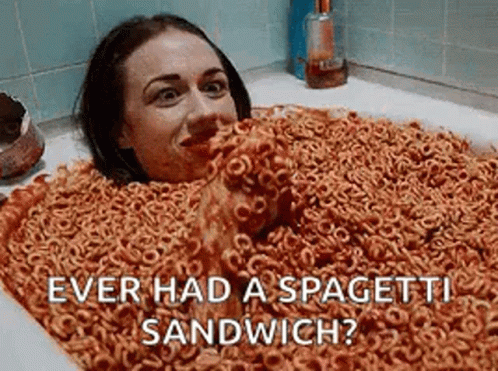 a woman is laying in a bathtub filled with cereal and spaghetti .
