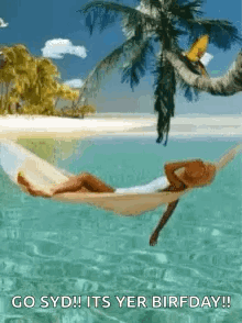 A Woman Is Laying In A Hammock In The Ocean On A Beach . GIF
