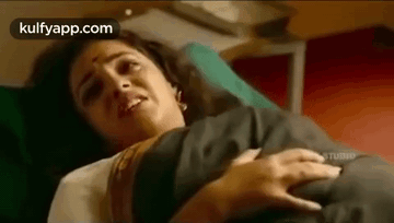 A Woman Is Laying In A Hospital Bed With A Baby In Her Arms . GIF