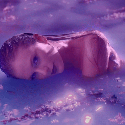 A Woman Is Laying In A Purple Bathtub GIF