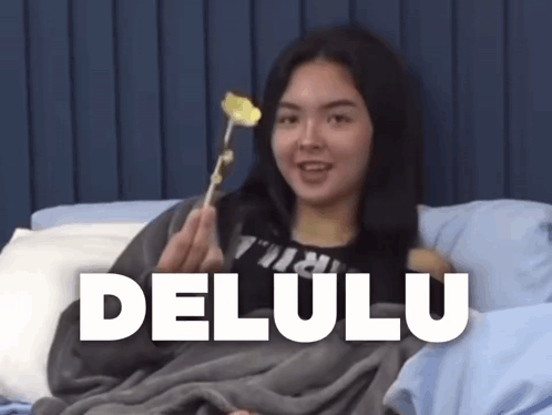 A Woman Is Laying In Bed Holding A Flower And The Word Delulu Is On The Bottom Right GIF
