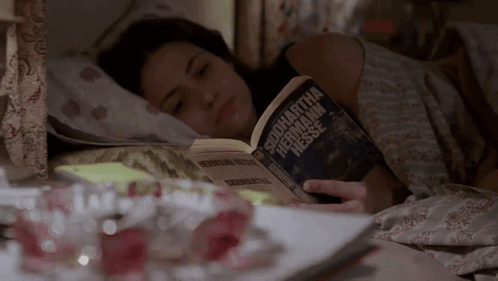 A Woman Is Laying In Bed Reading A Book By Samantha Hermann Hessen GIF