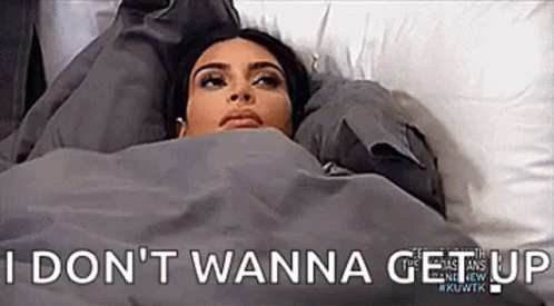 A Woman Is Laying In Bed Under A Blanket With The Words `` I Do N't Wanna Get Up '' . GIF