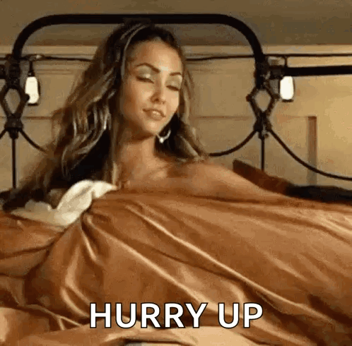 A Woman Is Laying In Bed With A Brown Blanket And A Brown Blanket . GIF