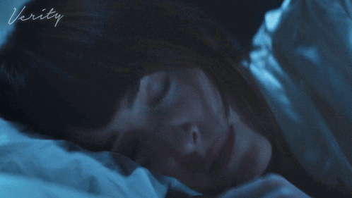 A Woman Is Laying In Bed With The Word Verity On The Bottom GIF