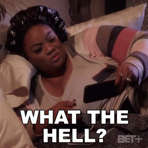 A Woman Is Laying On A Bed Holding A Cell Phone And Says What The Hell ? GIF