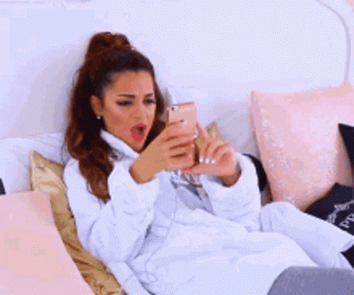 A Woman Is Laying On A Bed Wearing A White Robe . GIF