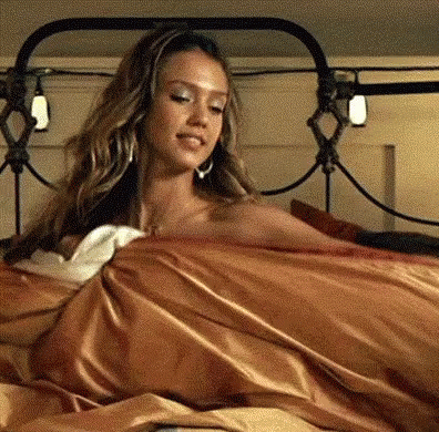 A Woman Is Laying On A Bed With A Blanket On Her . GIF