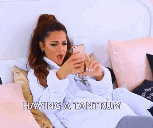 a woman is laying on a bed with the words having a tantrum written above her .