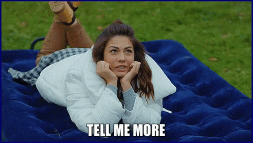 A Woman Is Laying On A Blue Mattress With The Words Tell Me More Written Below Her GIF