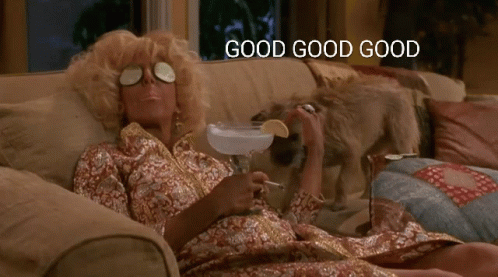 A Woman Is Laying On A Couch Holding A Martini And Smoking A Cigarette With The Words Good Good Good Above Her GIF