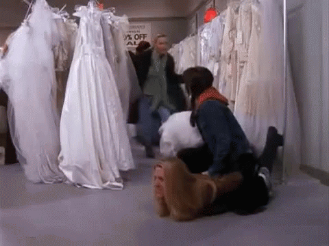 A Woman Is Laying On A Man 'S Lap In A Bridal Shop . GIF