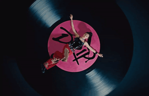 A Woman Is Laying On A Record That Has The Word Drip On It GIF