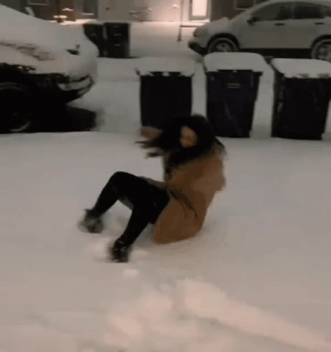 A Woman Is Laying On Her Back In The Snow In A Parking Lot GIF