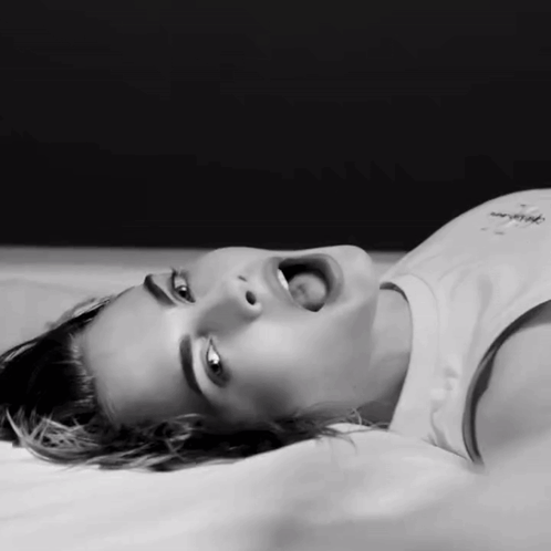 A Woman Is Laying On Her Back With Her Mouth Open GIF