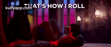 A Woman Is Laying On Her Stomach On A Bed In A Dark Room . GIF
