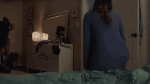 A Woman Is Laying On Her Stomach On A Bed With Her Legs Up . GIF