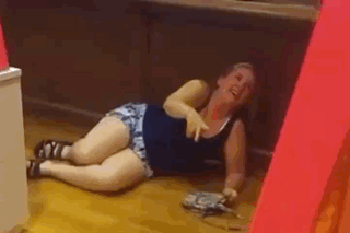 A Woman Is Laying On The Floor Laughing And Holding A Purse . GIF