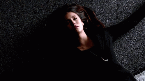 A Woman Is Laying On The Ground In A Dark Room . GIF