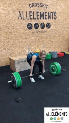 A Woman Is Lifting A Barbell In Front Of A Wall That Says Crossfit Alleements GIF