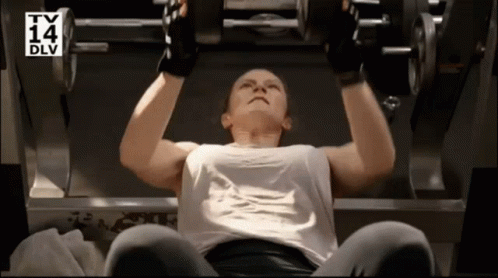 A Woman Is Lifting A Dumbbell In A Gym With A Tv 14 Dlv Logo Behind Her GIF