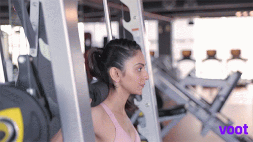 A Woman Is Lifting Weights In A Gym And The Word Voot Is On The Bottom Right GIF