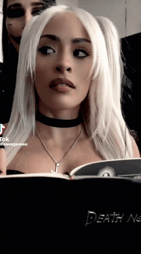 A Woman Is Looking At A Book Titled Death Note GIF