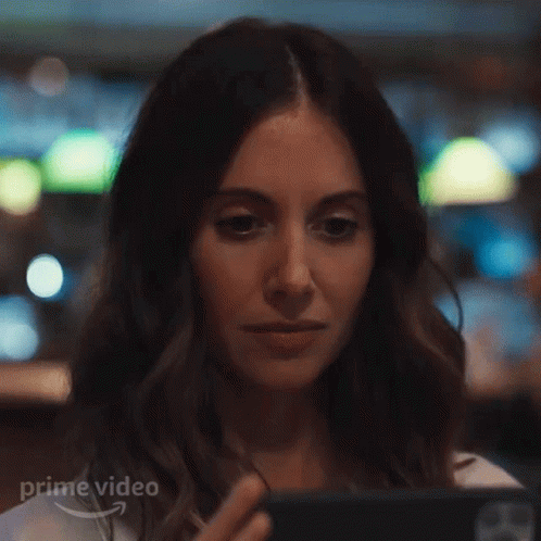 A Woman Is Looking At A Cell Phone In A Restaurant . GIF