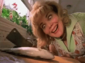 A Woman Is Looking At A Fish On A Cutting Board And Smiling . GIF