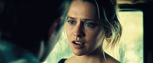 A Woman Is Looking At A Man In A Dark Room And Making A Funny Face . GIF
