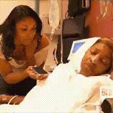 A Woman Is Looking At A Man In A Hospital Bed GIF