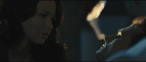 A Woman Is Looking At A Man Laying In A Bed GIF