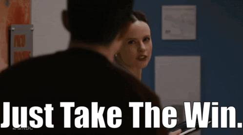 A Woman Is Looking At A Man With The Words Just Take The Win Behind Her GIF