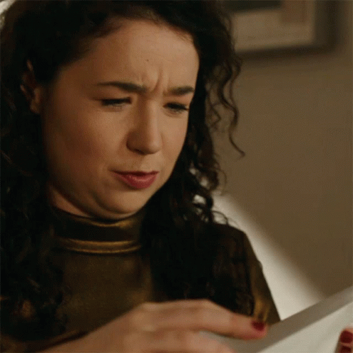 A Woman Is Looking At A Piece Of Paper And Making A Funny Face GIF