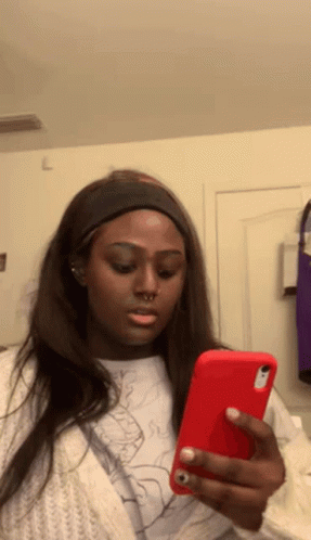 a woman is looking at her phone and making a face .