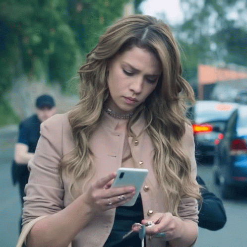 A Woman Is Looking At Her Phone While Holding Keys GIF