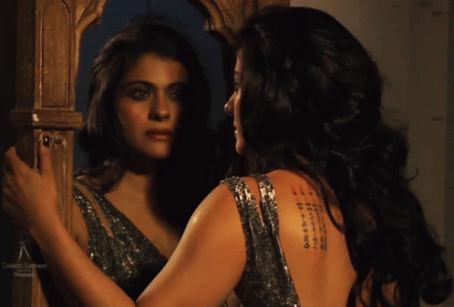 A Woman Is Looking At Her Reflection In A Mirror With A Tattoo On Her Back GIF