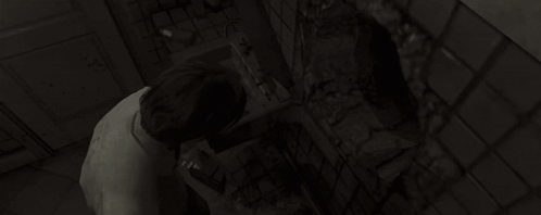 a woman is looking at herself in a mirror in a dark bathroom .