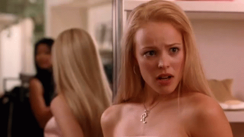 A Woman Is Looking At Herself In A Mirror While Wearing A Necklace . GIF