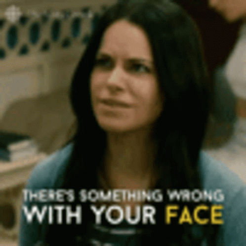 A Woman Is Looking At The Camera With The Words `` There 'S Something Wrong With Your Face '' Written Above Her . GIF