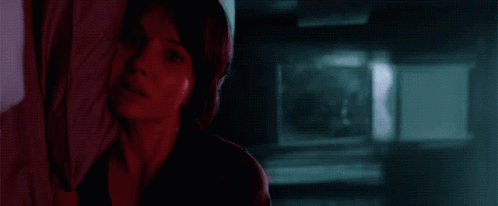 A Woman Is Looking Out A Window With A Blue Sky In The Background . GIF