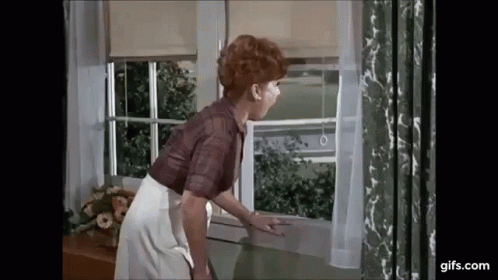 A Woman Is Looking Out Of A Window . GIF