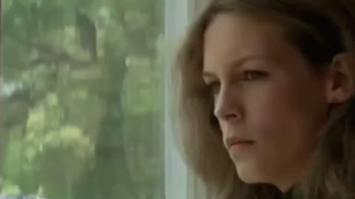 A Woman Is Looking Out Of A Window And Making A Serious Face . GIF