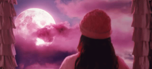 a woman is looking out of a window at a full moon .