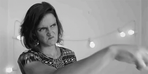 A Woman Is Making A Funny Face In A Black And White Photo While Holding Her Hand Up . GIF