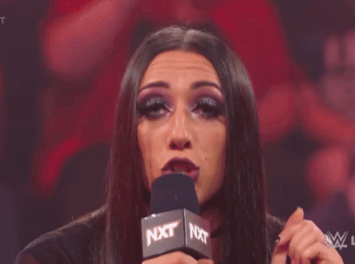 A Woman Is Making A Funny Face In Front Of A Crowd Of People . GIF