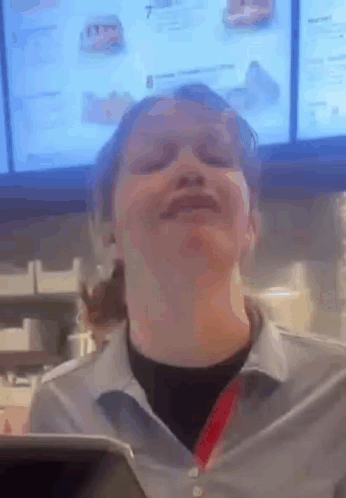 A Woman Is Making A Funny Face In Front Of A Menu In A Fast Food Restaurant . GIF