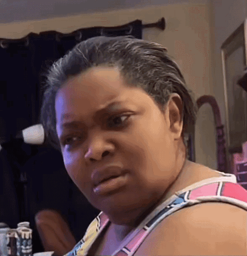 A Woman Is Making A Funny Face In Front Of A Mirror . GIF