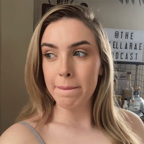 A Woman Is Making A Funny Face In Front Of A Sign That Says @The Ellarae Podcast GIF